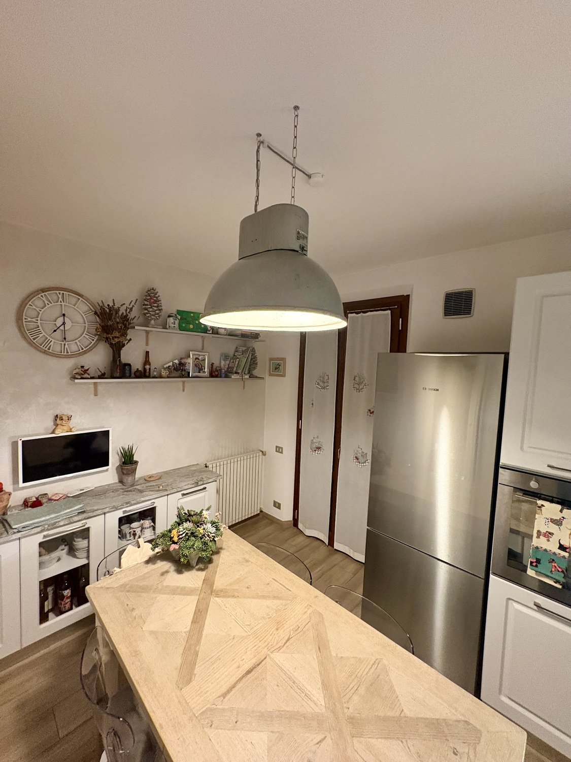 Cucina con grande sospensione in alluminio sopra il tavolo
